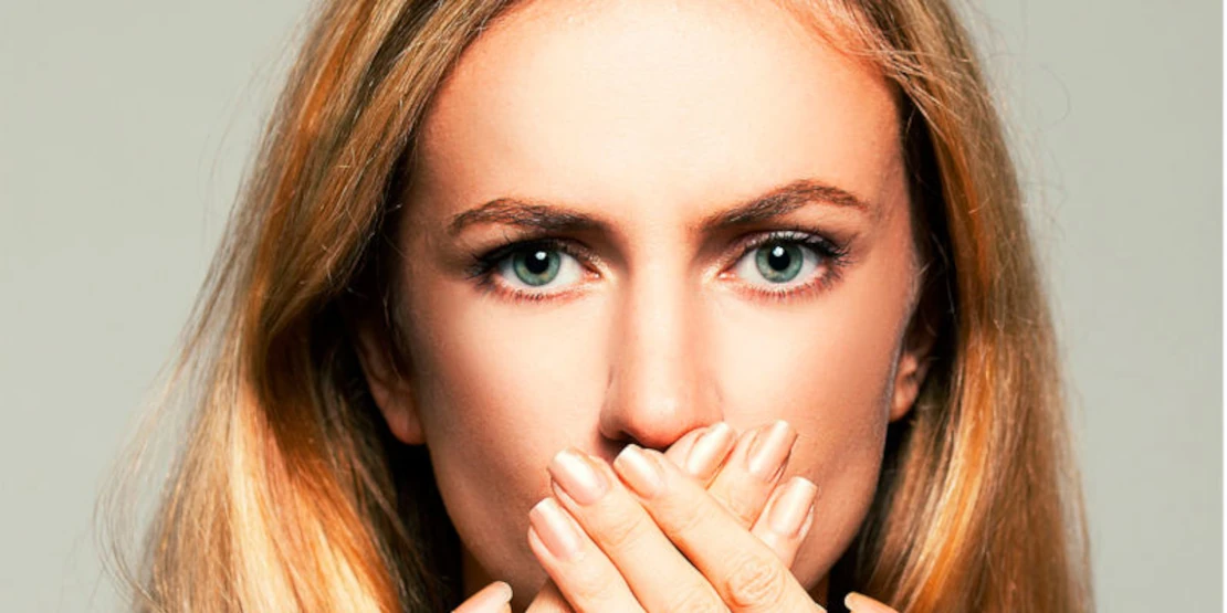 photo of a woman with stomatitis covering her mouth with two hands