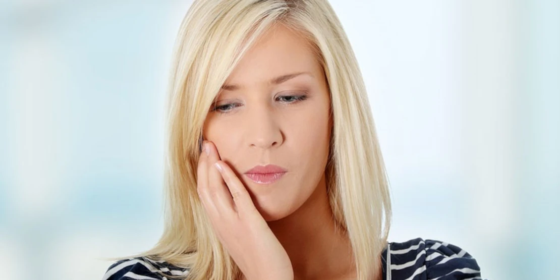 quality dental implantation in Ukraine; girl holding on to a sick tooth